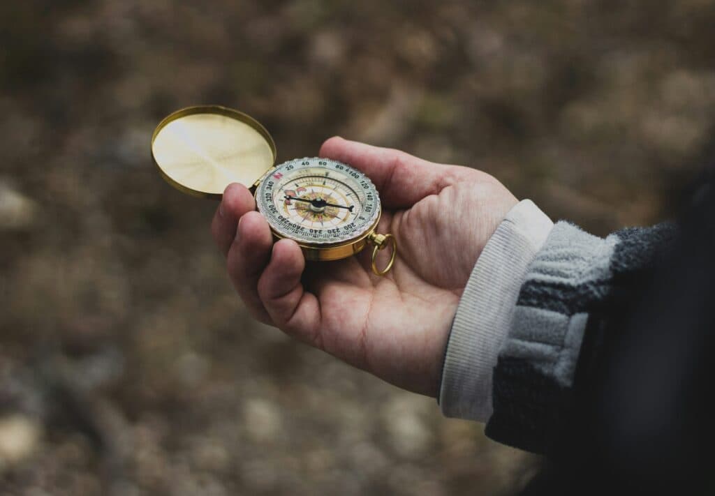 A hand holding a compass outdoors
